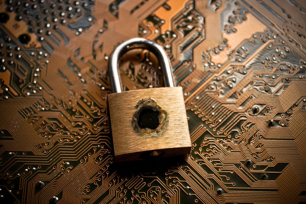 Data breach insurance. A penetrated security lock with a hole on computer circuit board background.