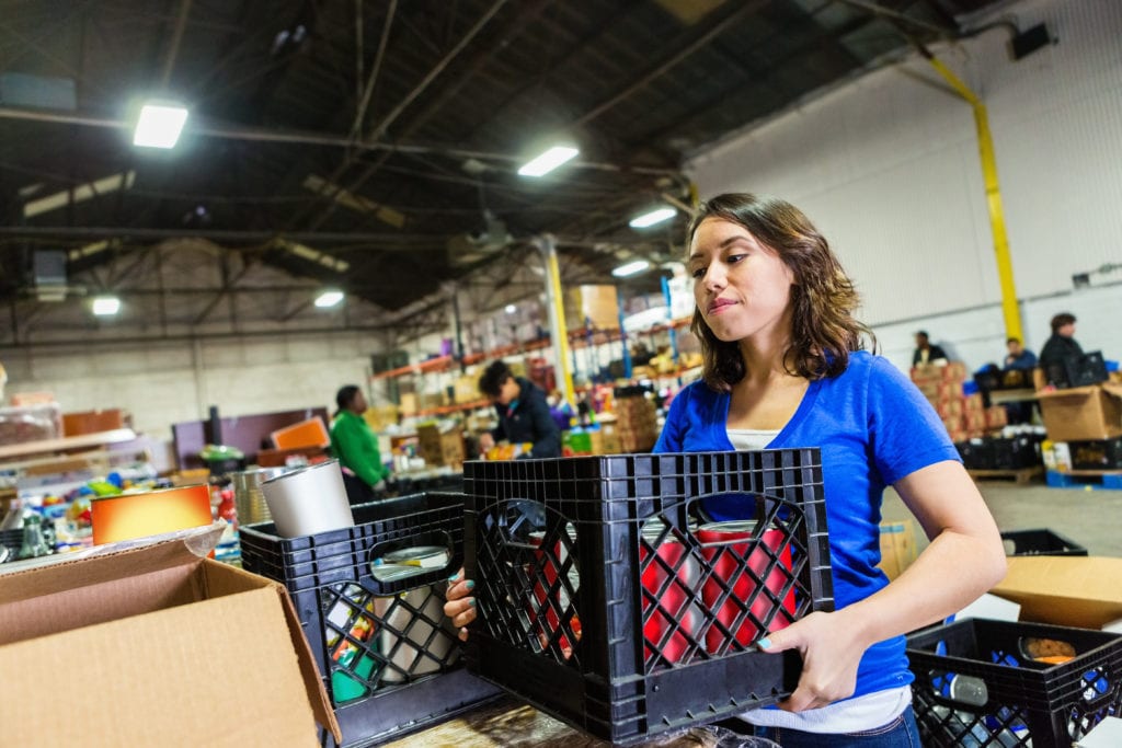 Social services insurance property, a volunteer organizing donated items inside a warehouse.