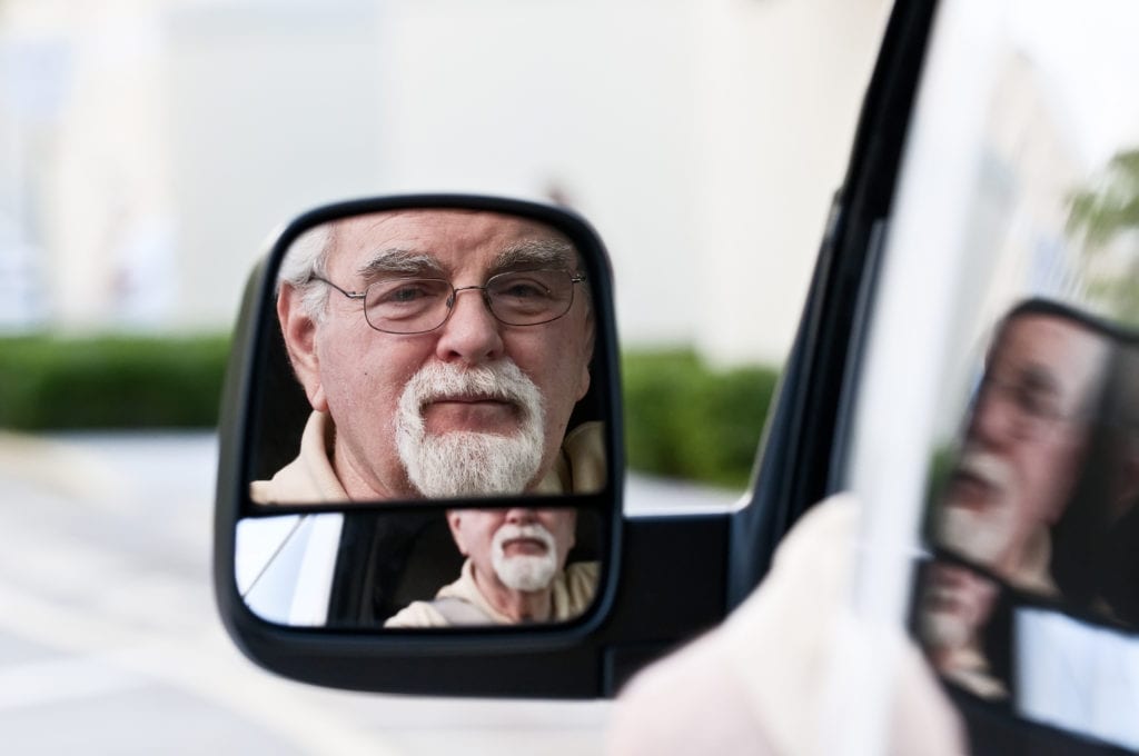 NEMT workers compensation insurance driver looking in rearview mirror