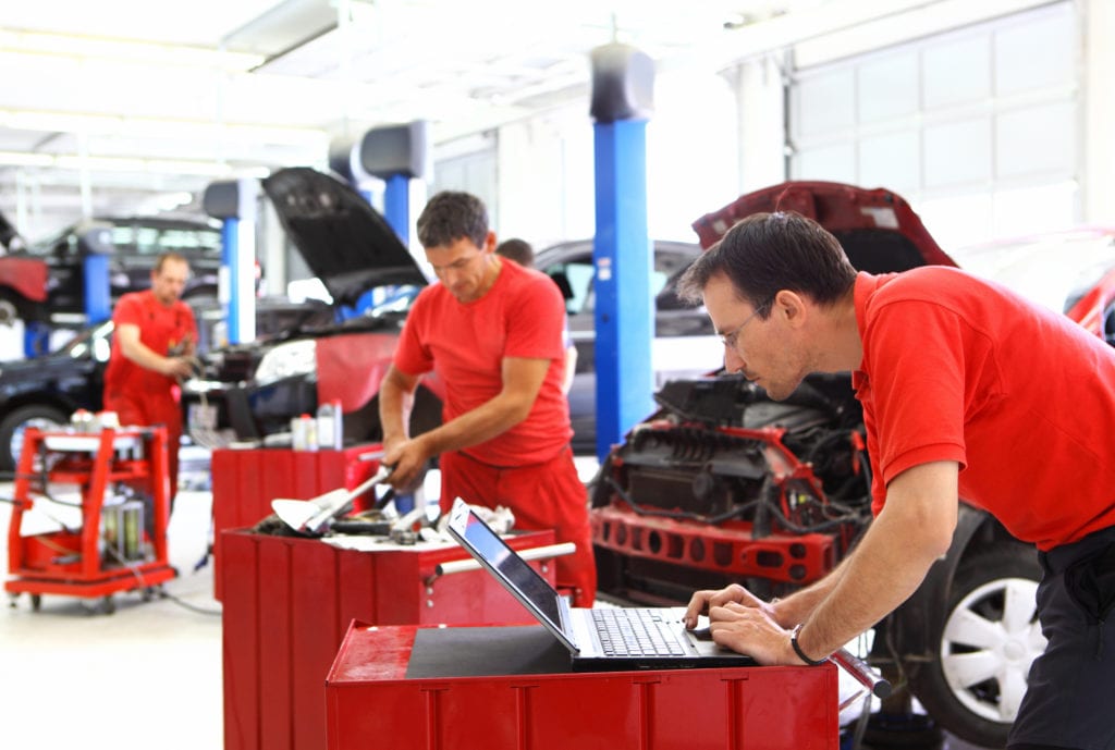 Garage insurance workers compensation coverage. Group car mechanics performing maintenance.