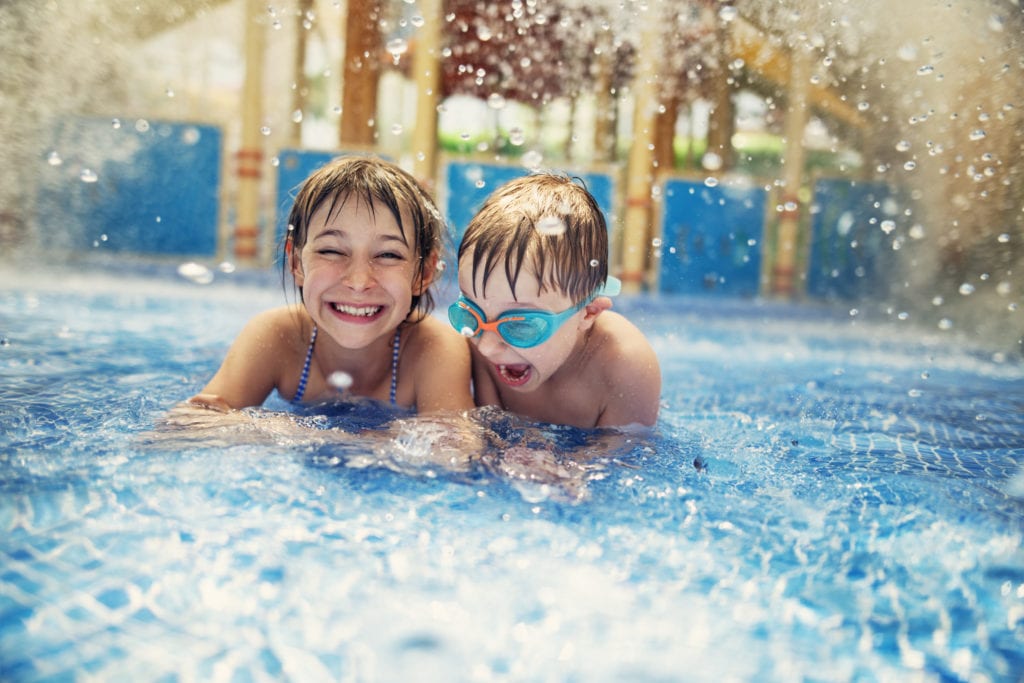 Motel insurance liability coverage. Two young children smiling and playing in motel pool.
