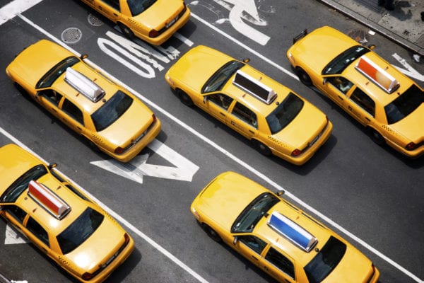 Public auto minimum liability limits, yellow taxi cabs make their way down the street of Broadway in New York City.