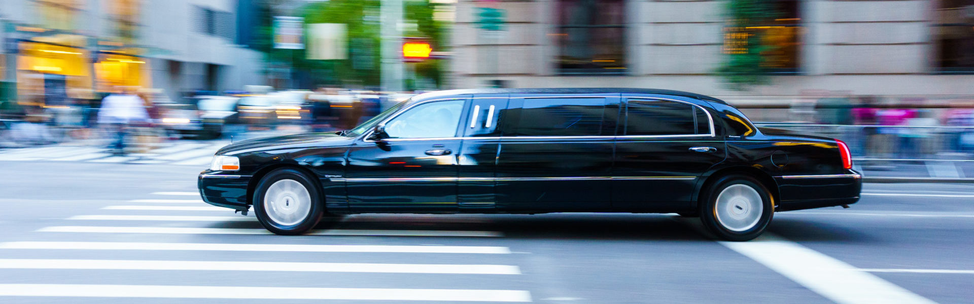 Livery insurance limo header, a black limousine driving in Manhattan, blurred background.
