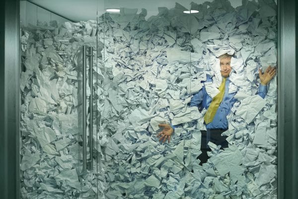 Paper or PDF, businessman smashed against glass wall by paper. Paperless office.