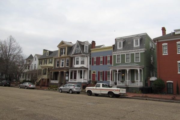 Residential street of downtown Portsmouth, VA, lined with multi colored victorian style townhomes.