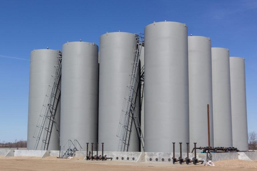 Insurance for fuel oil dealers property inland marine, grid of sixteen gray vertical storage tanks, tank farm.