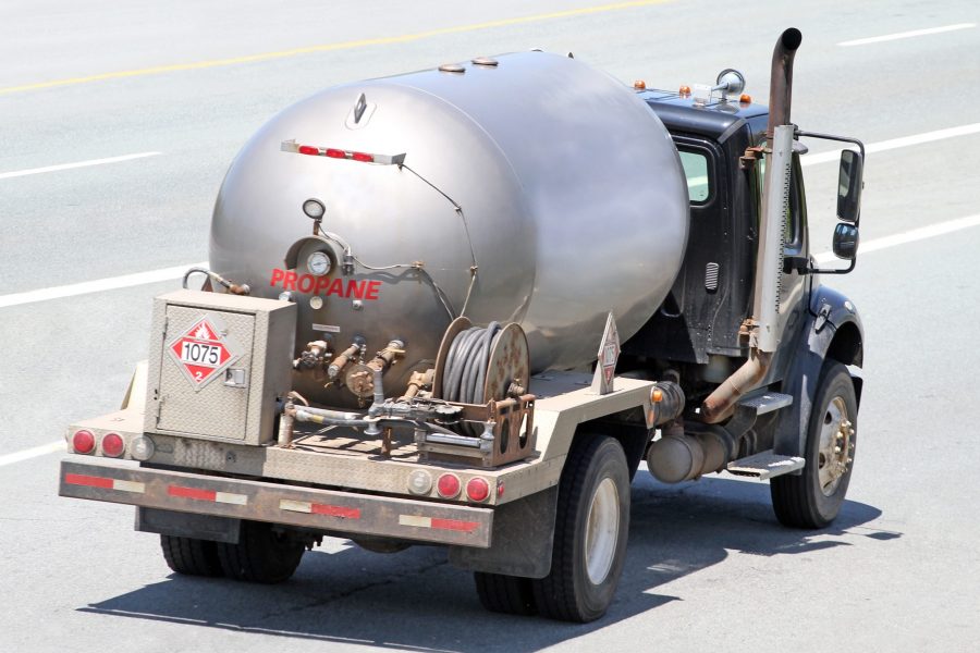 Insurance for propane dealers business auto, rear view of silver tank propane delivery truck on highway.