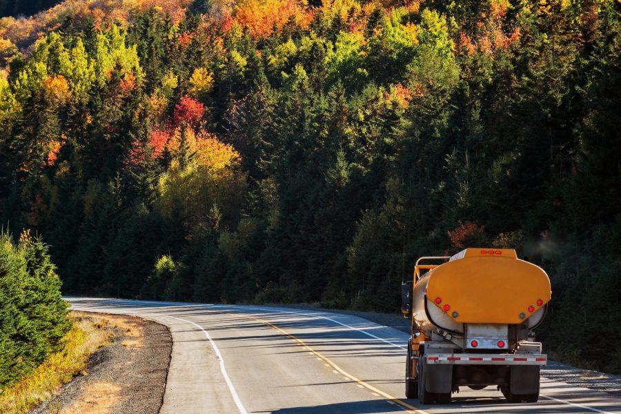 Insurance for propane dealers fueling our clients, fuel oil truck on mountain highway, trees in background in autumn colors.