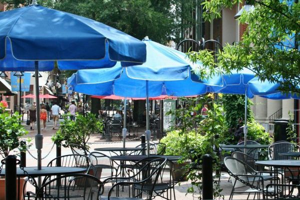 Charlottesville, VA insurance agency, downtown outdoor cafe with iron tables and blue umbrellas on brick street.