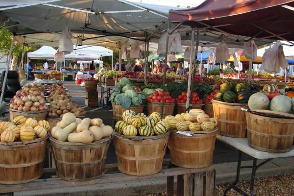 Danville, VA Farmers Market. Bushel baskets of vegetables, gourds, and melons on tables in outdoor market.