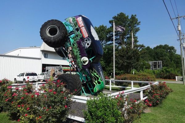 Elizabeth City, NC, monster truck graveyard, Digger's Dungeon, large green truck nosed into the ground before white metal building.