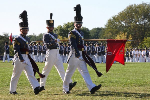 Lexington, VA Virginia Military Institute, parade on green field, three cadets in uniform of white pants and blue-gray felted wool jackets pass in review.
