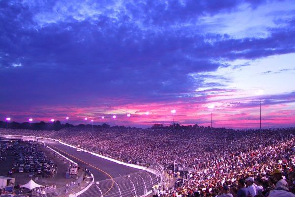 Richmond, VA blue, pink, and fuschia sunset over oval raceway with stands packed with NASCAR fans.