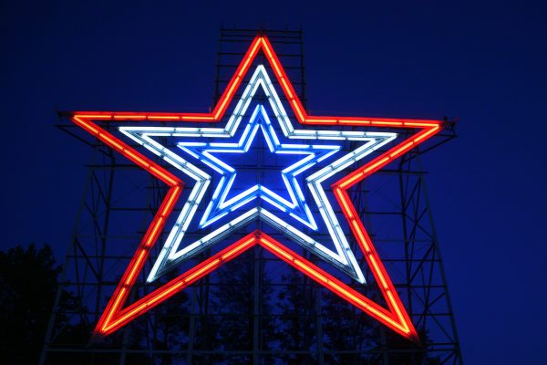 Roanoke, VA Mill Mountain Star shown at night, blue neon center with repeated larger neon lights in white and red surrounding it.