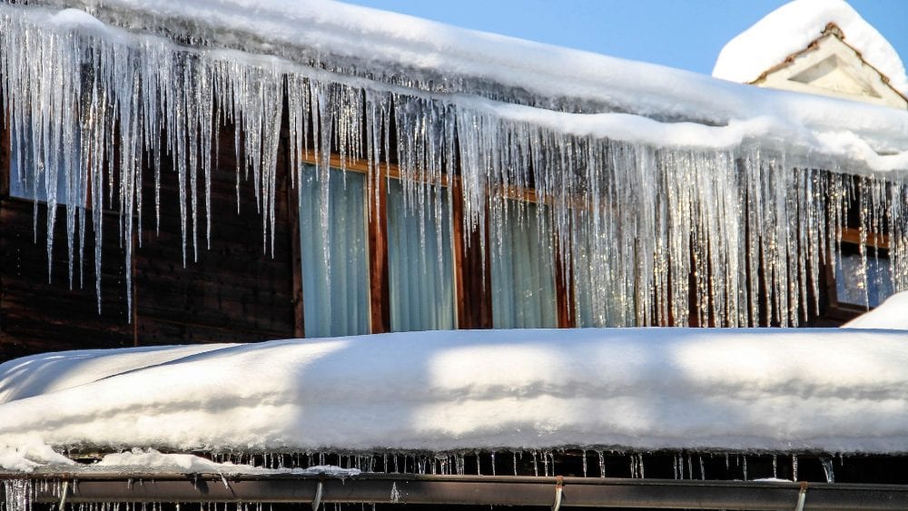 Prevent Frozen Pipes and Winter Weather Damage, ice sickles hanging from gutter of home.