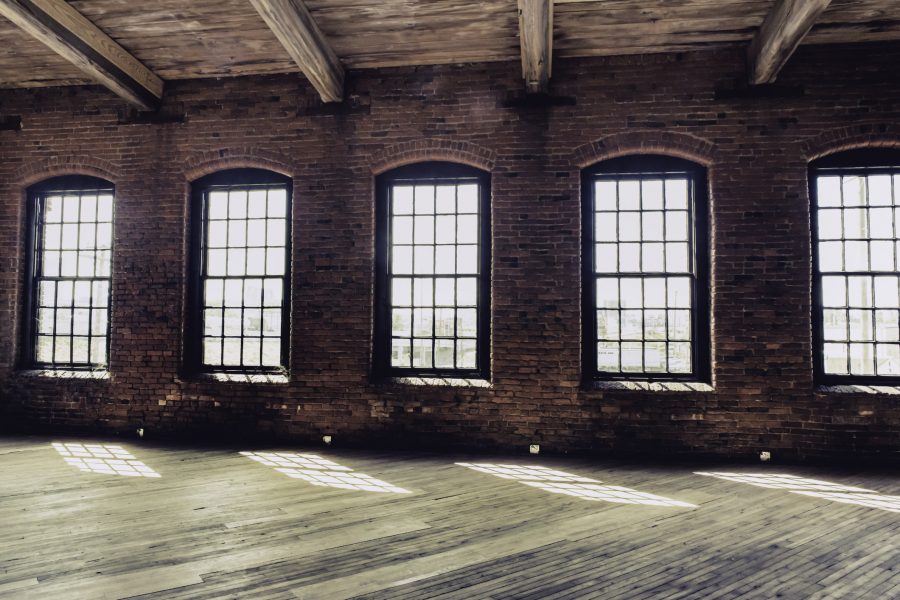Windows in an old brick warehouse with wooden floor. Actual Cash Value insurance valuation method considers depreciation of the structure.