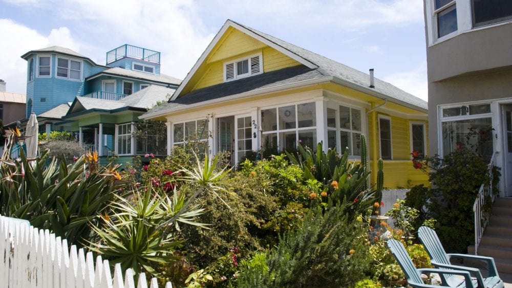 Colorful beach houses with white picket fence for home-sharing and rental insurance.
