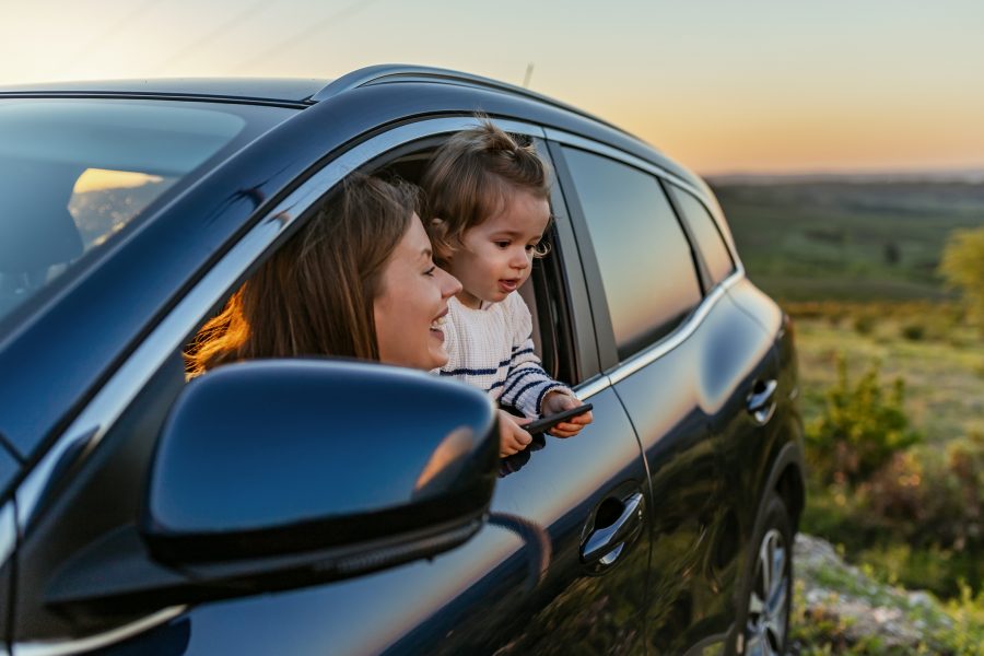 Woman and child in car on side of road enjoying the view, representing car insurance client.