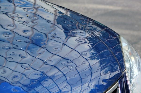 Hail-dented car hood. Hail is covered under the comprehensive portion of a car insurance policy.