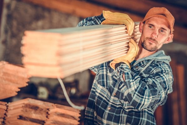 Construction worker shouldering planks of wood representing the need to transfer contractual risk.