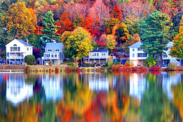 Lakeside home insurance houses surrounded with bright fall trees.