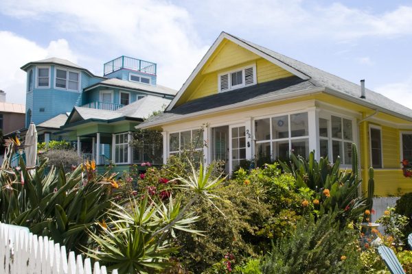 Row of colorful specialty home insurance beach houses with white picket fencing.