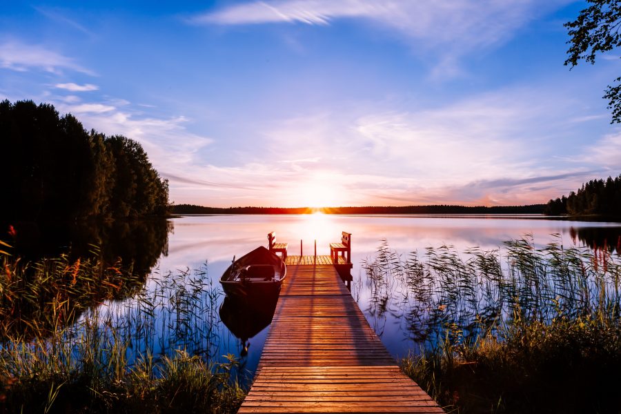 Wooden dock at sunrise with small boat.