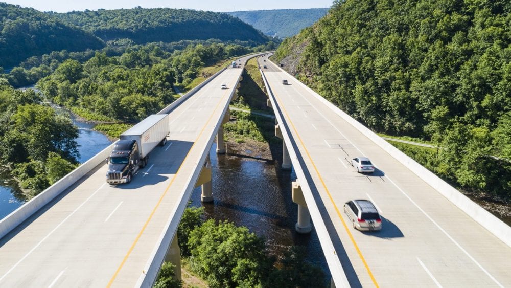 Private passenger vehicles and trucks on a bridge.