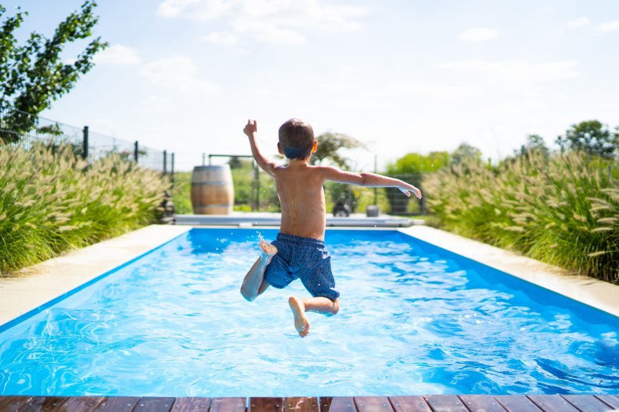 Boy jumping into a swimming pool.