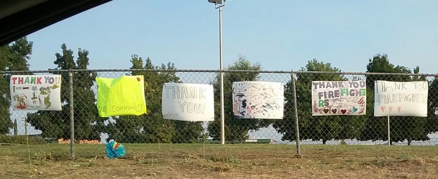 Many paper signs on chain link fence announcing support of all those helping during the Kincade fire.
