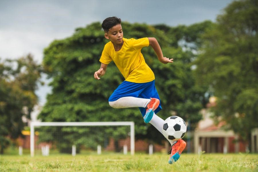Young, healthy child playing soccer representing the perfect time to buy life insurance for kids.