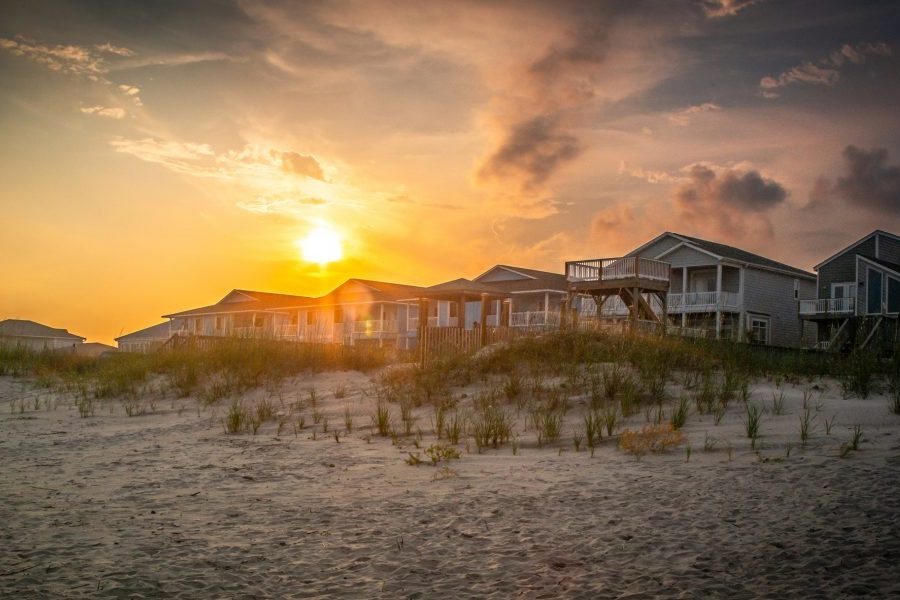 A brilliant sky hovers over vacation homes atop sand dunes.
