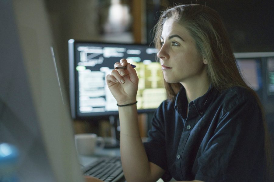 A young woman seated at desk staring at computer and contemplating theft.