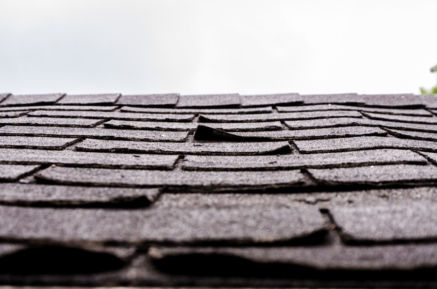 Closeup of curling, worn shingles which could lead to a roof insurance claim.