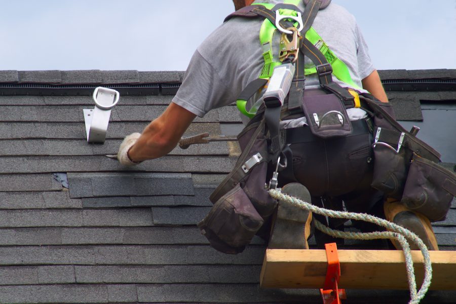 Construction worker repairing a partially damaged roof to avoid a roof insurance claim.
