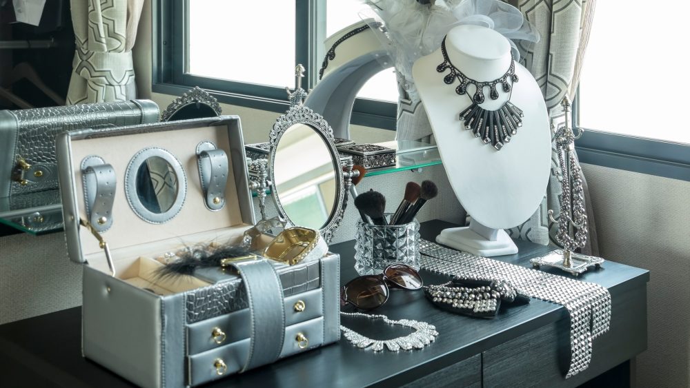 Jewelry box with jewelry on table in front of mirror.