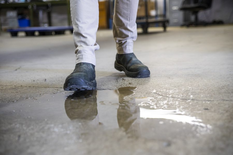 Warehouse worker in boots stepping onto wet floor.