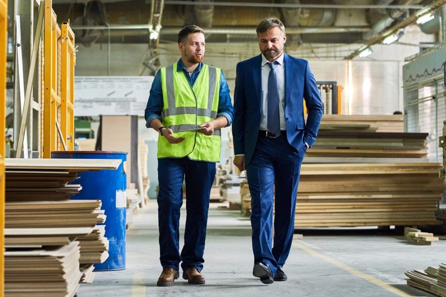 Business owners walking in wood factory discussing buy-sell agreement insurance.