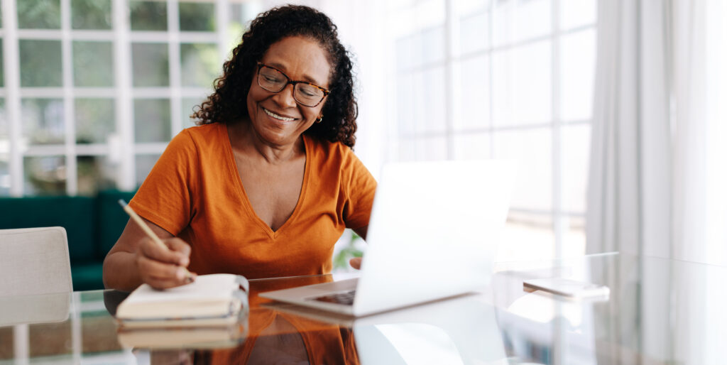 A retired older woman planning for her future finances and smiling in her living room.